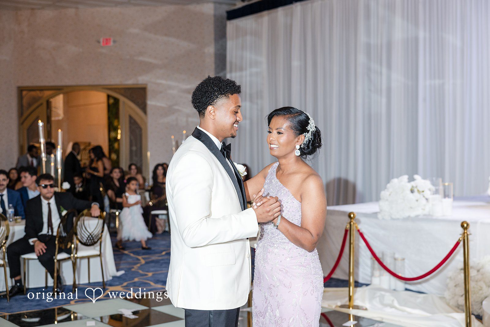 A groom slow dancing with a woman wearing a light pink dress.