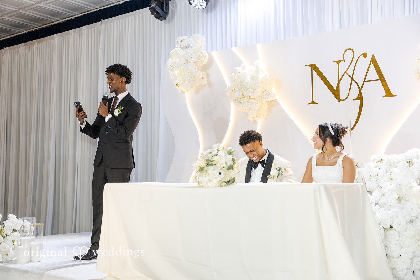 A man speaking into a microphone next to a decorated table.