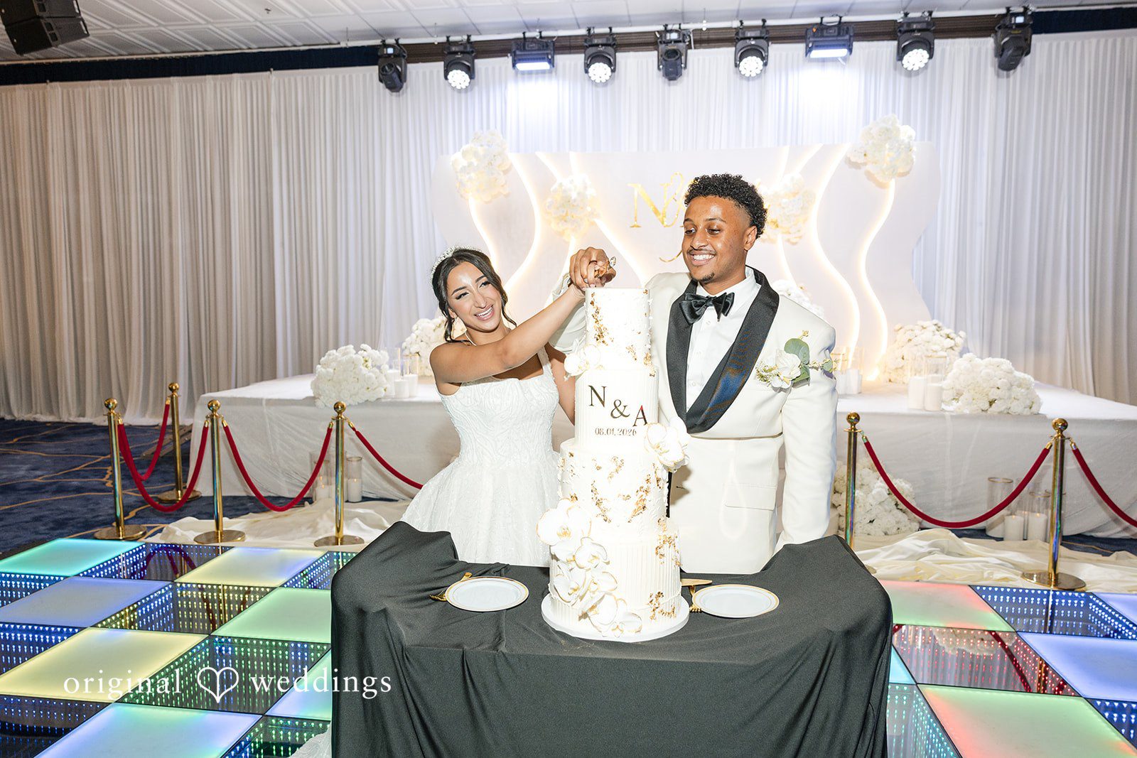 A bride and groom cutting their multi-tiered white wedding cake.