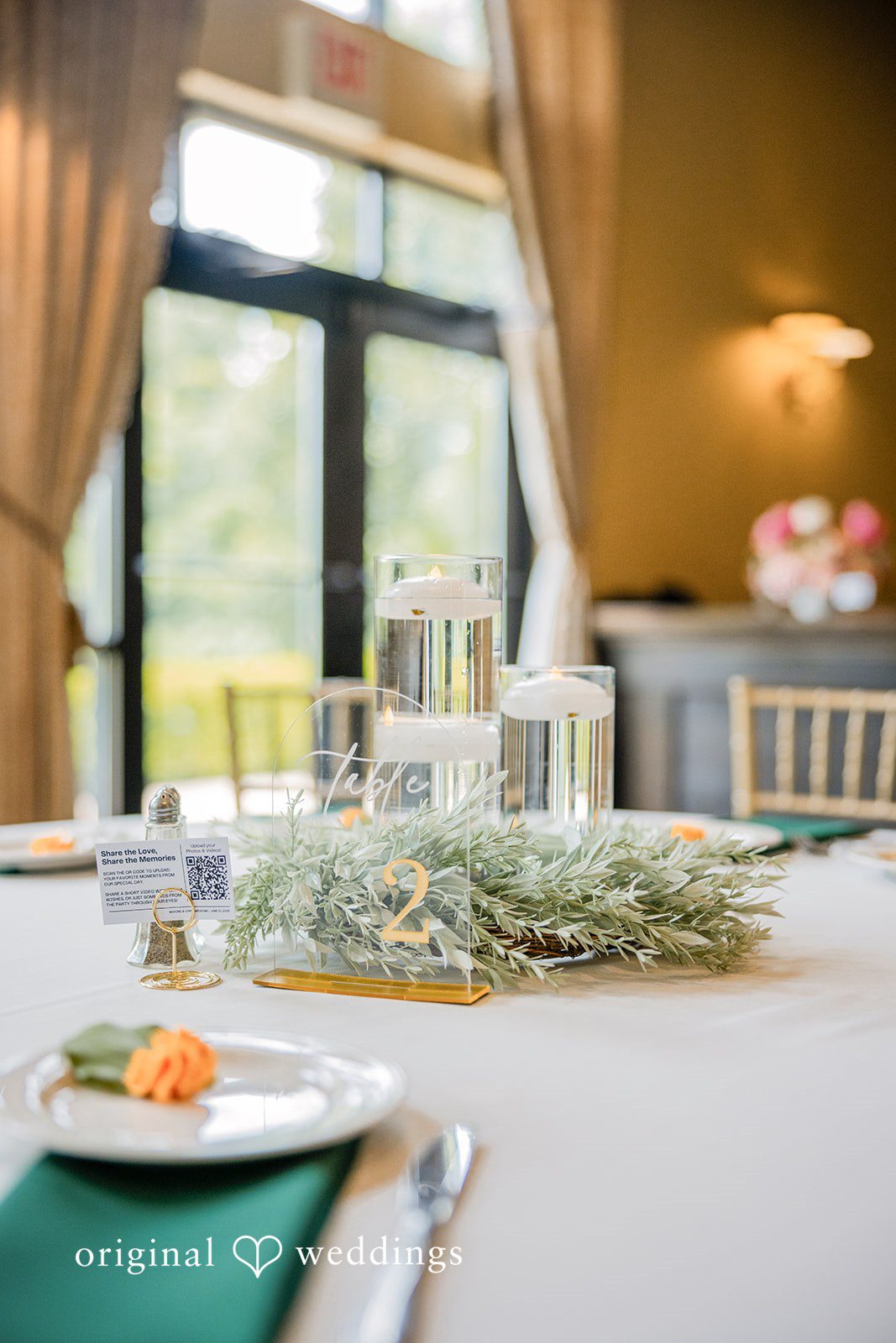 Christopher + Maxine Wedding reception table setting featuring a green tablecloth, white floral centerpiece, and glassware.