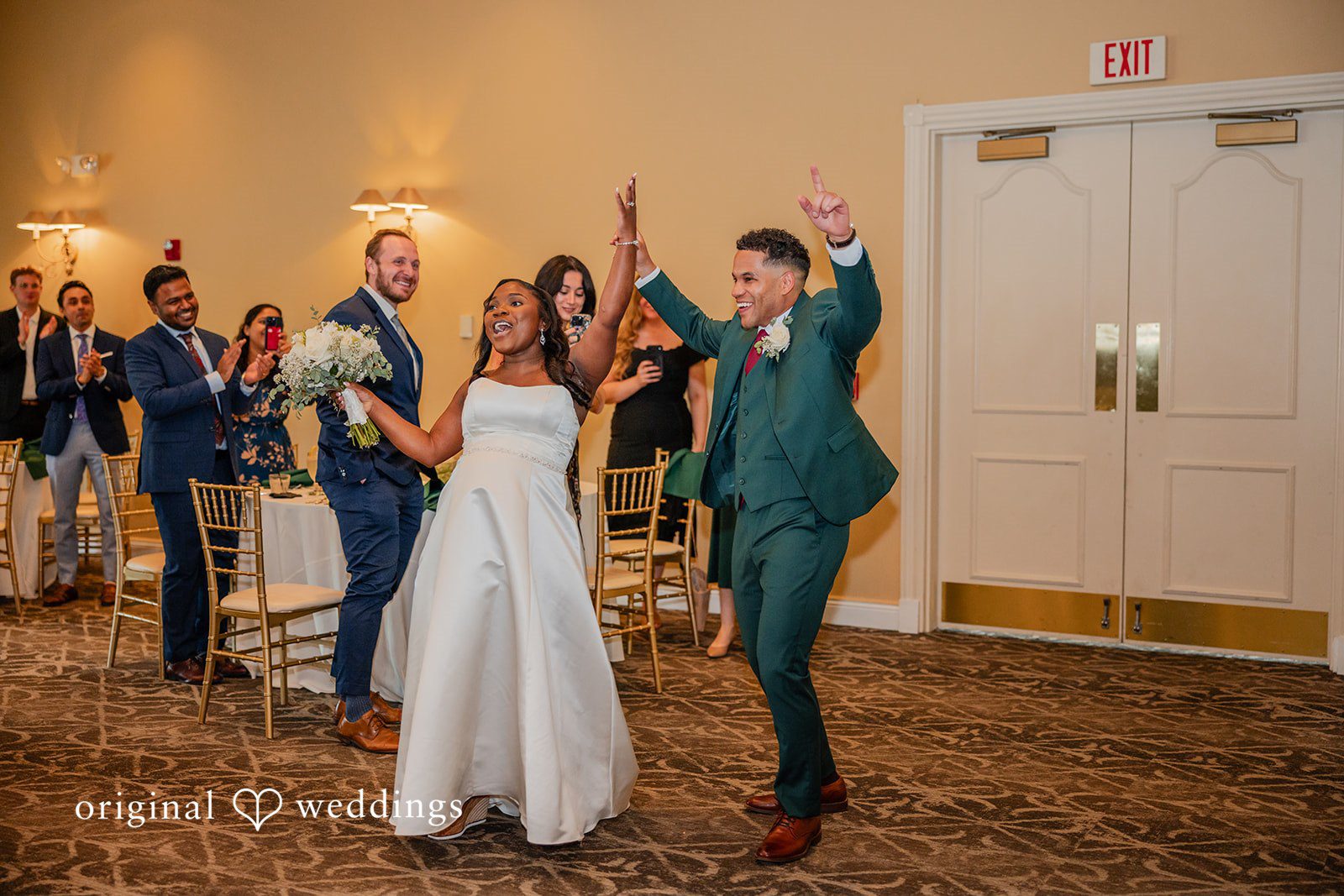 Christopher + Maxine Newlyweds making a grand entrance into a reception hall while cheering guests look on