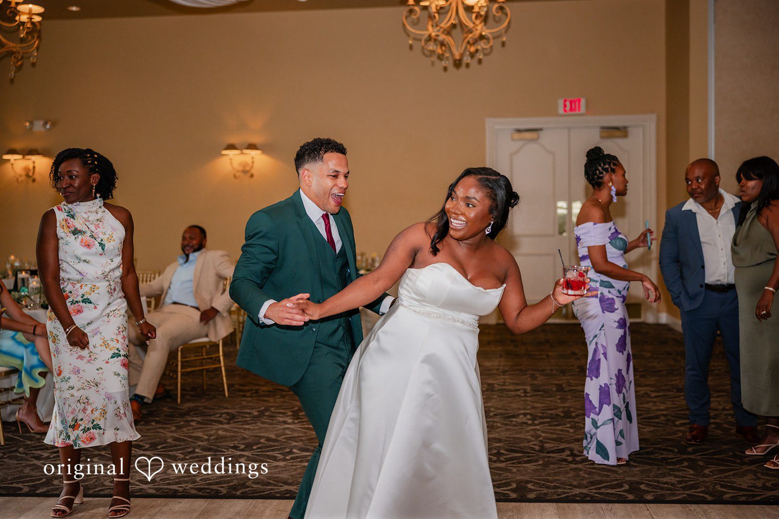Christopher + Maxine Newlyweds laughing and dancing together in the center of a reception hall.