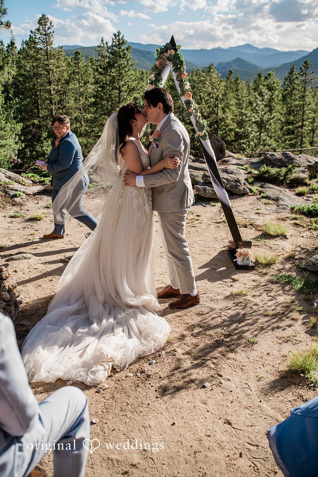 Madelyn + Erin A bride and groom embracing on a rocky mountain ledge.