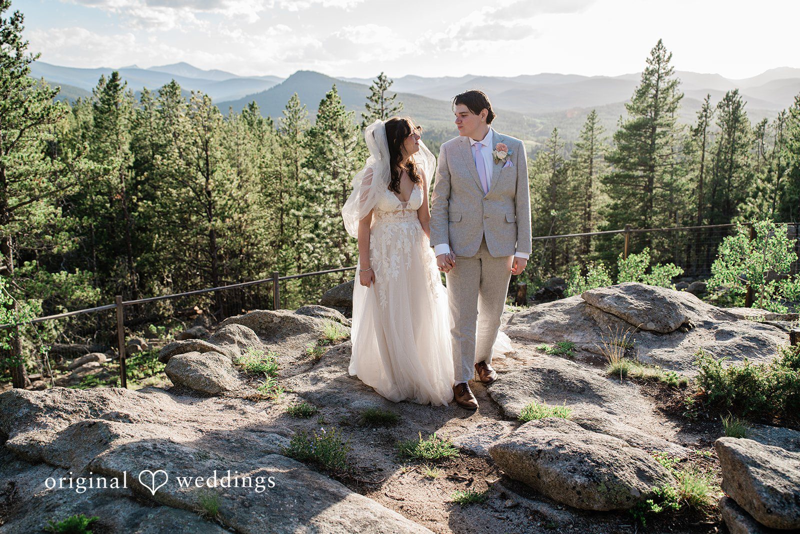 Madelyn + Erin A bride and groom standing together on a high rocky mountain peak.