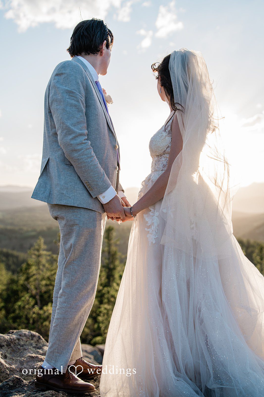 Madelyn + Erin A bride and groom holding hands and facing each other at sunset.