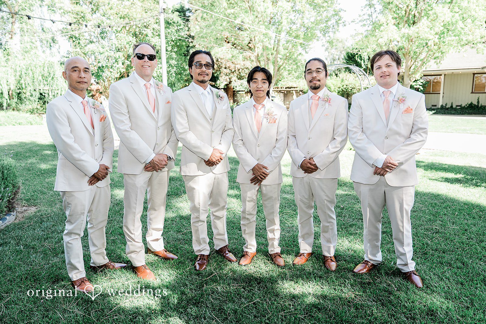 Lindsay + Ryan A groom standing with his groomsmen all dressed in matching light-colored linen suits.