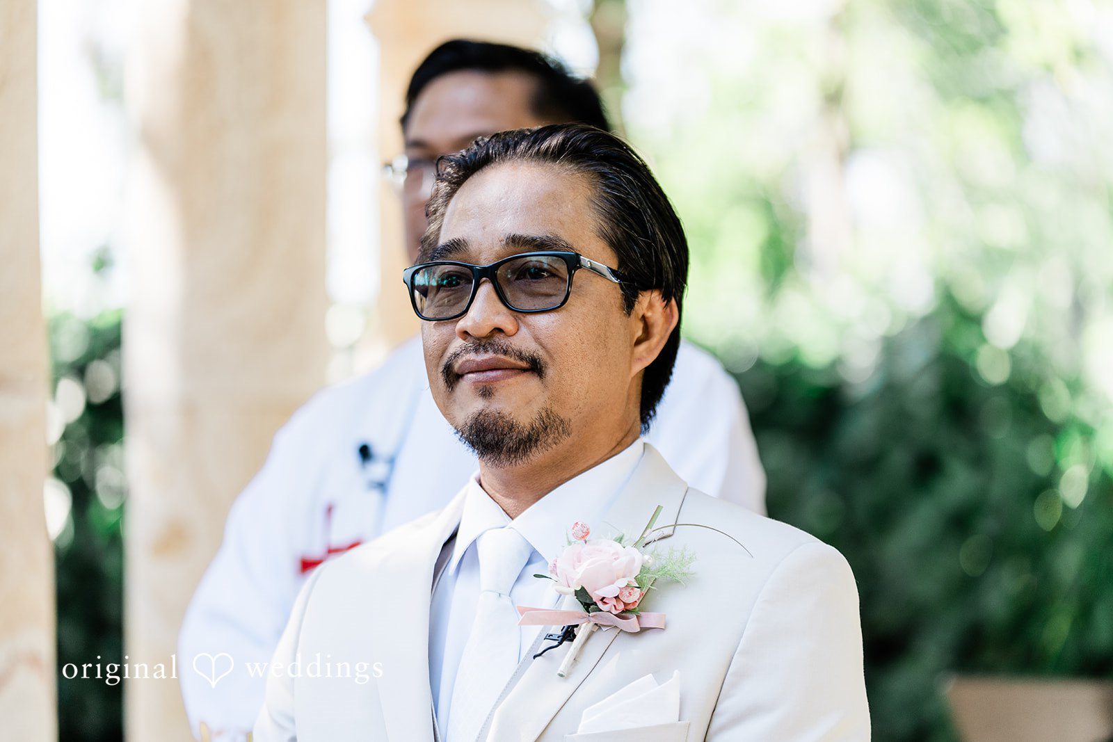 Lindsay + Ryan A groom looking forward thoughtfully while wearing a white suit and dark sunglasses.