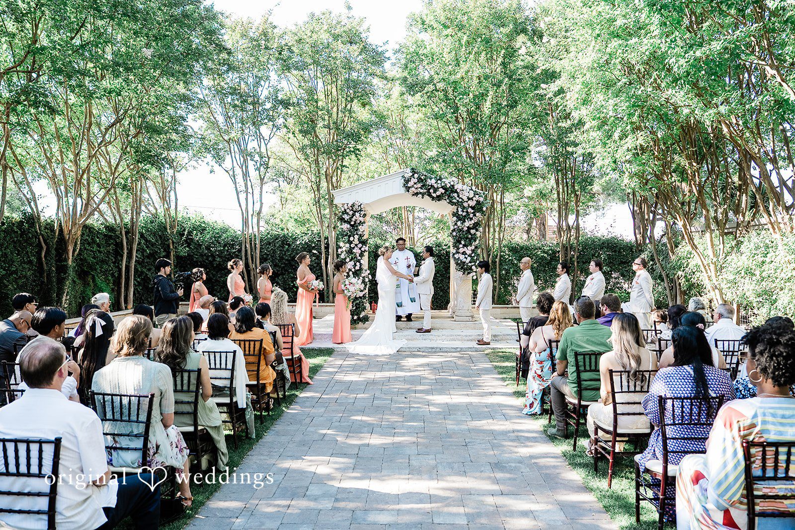 Lindsay + Ryan A wedding aisle lined with guests and floral arrangements leading toward a decorated altar.
