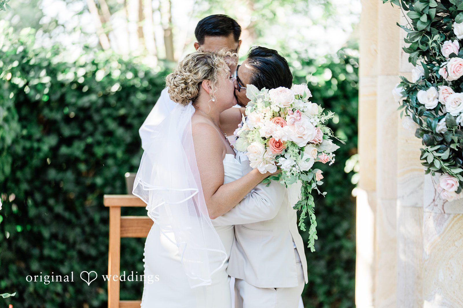 Lindsay + Ryan A bride and groom embracing under a floral archway during their wedding ceremony.