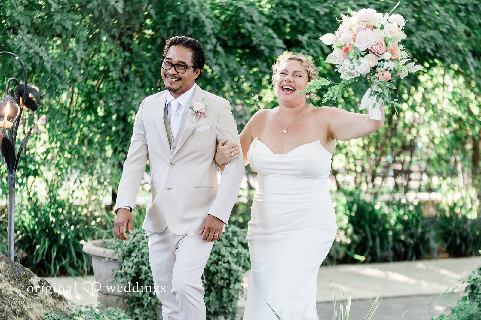 Lindsay + Ryan A bride and groom walking hand-in-hand through a lush green garden setting.