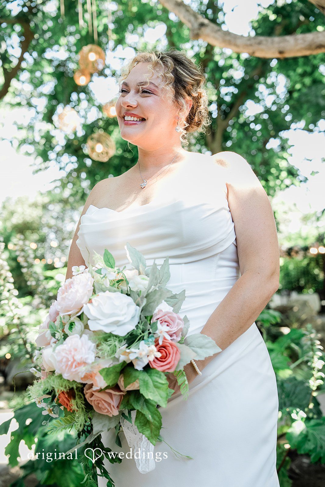 Lindsay + Ryan A bride in a sleeveless white gown holding a large pastel bouquet while smiling.