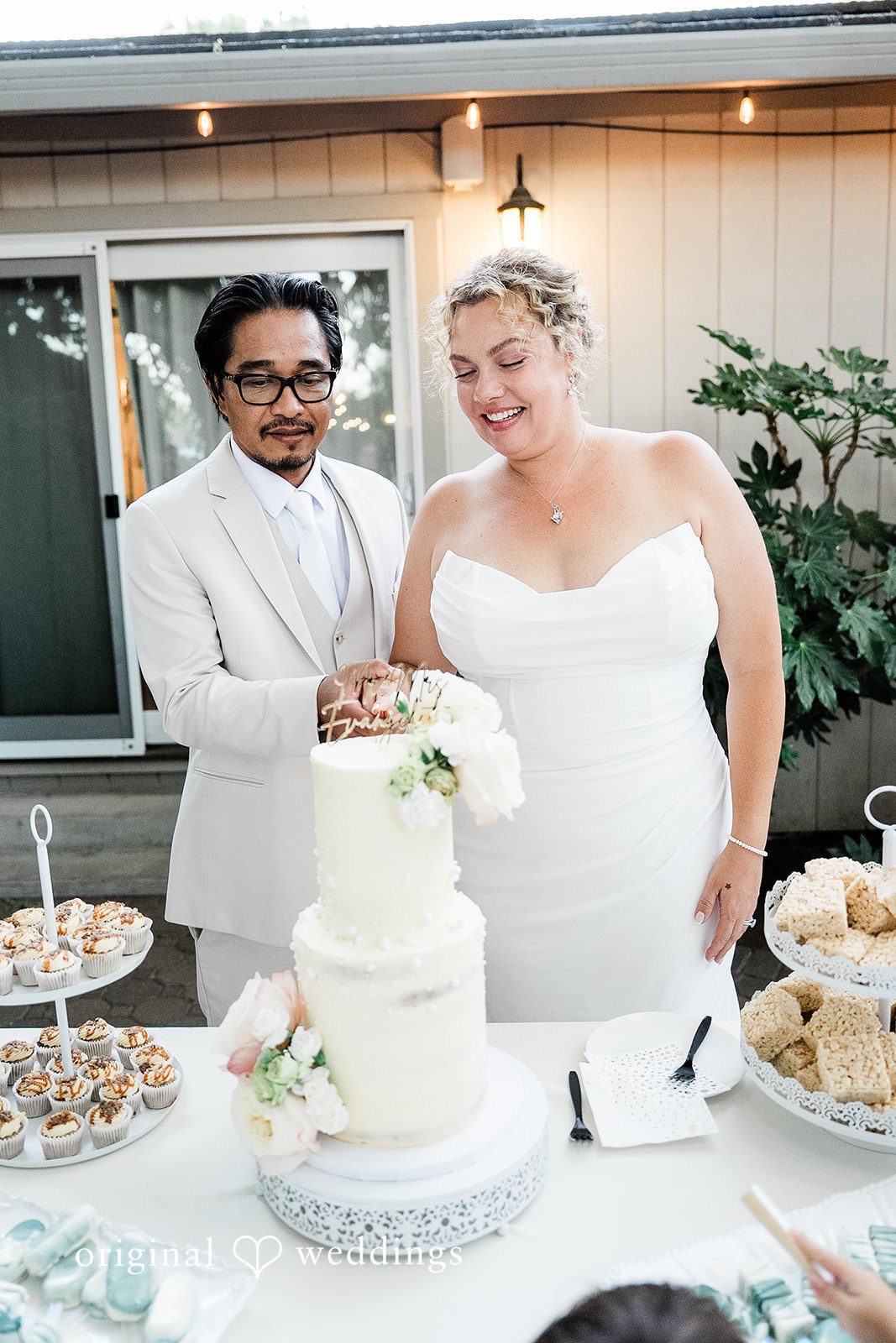 Lindsay + Ryan A bride and groom standing next to their tiered wedding cake during the reception.