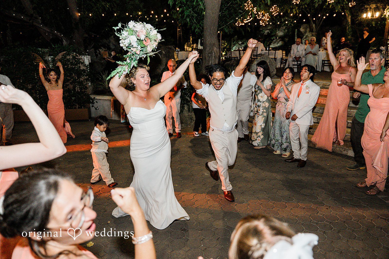 Lindsay + Ryan A bride and groom dancing excitedly with their hands raised high during the party.