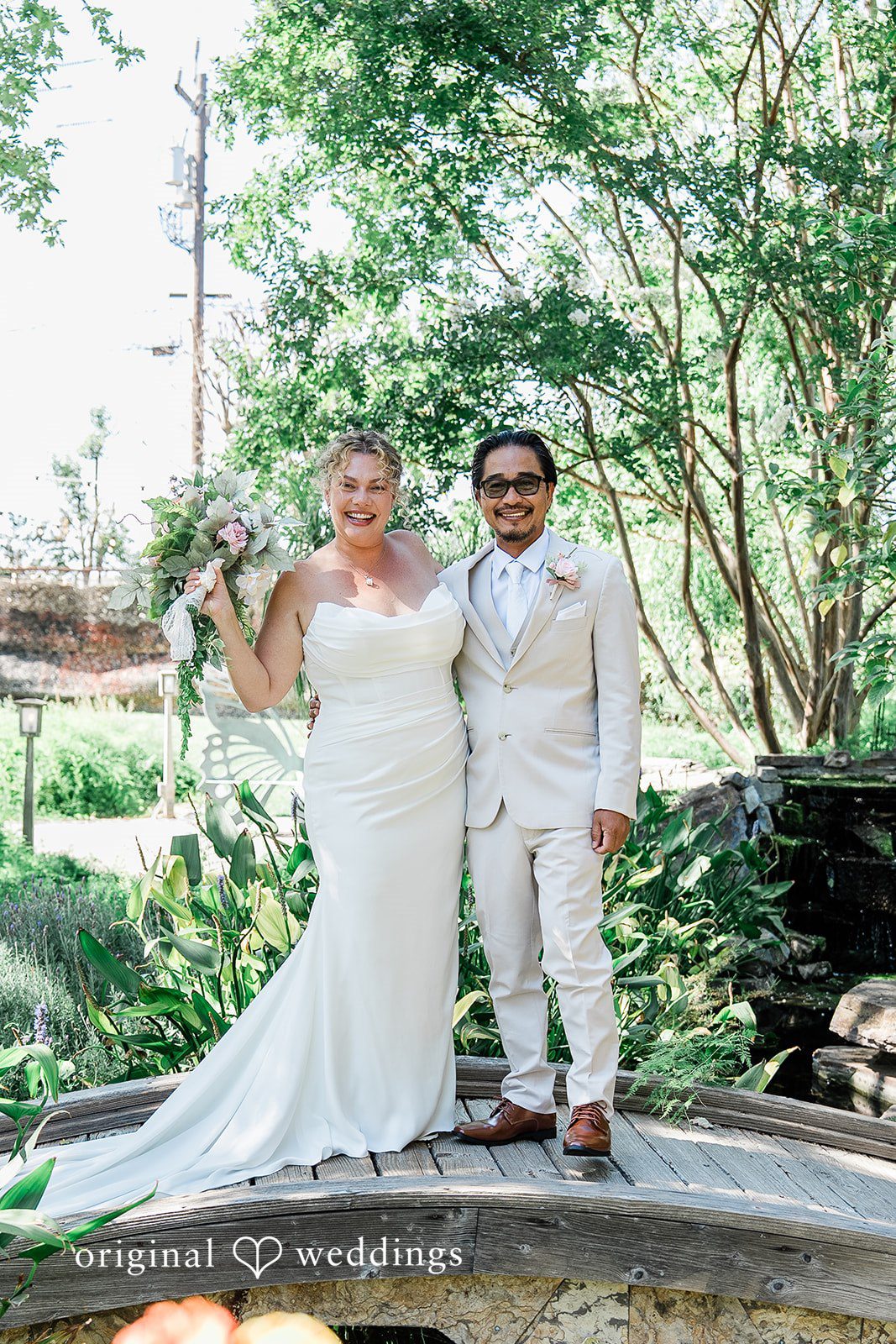 Lindsay + Ryan A bride and groom standing together on a stone pathway surrounded by greenery.