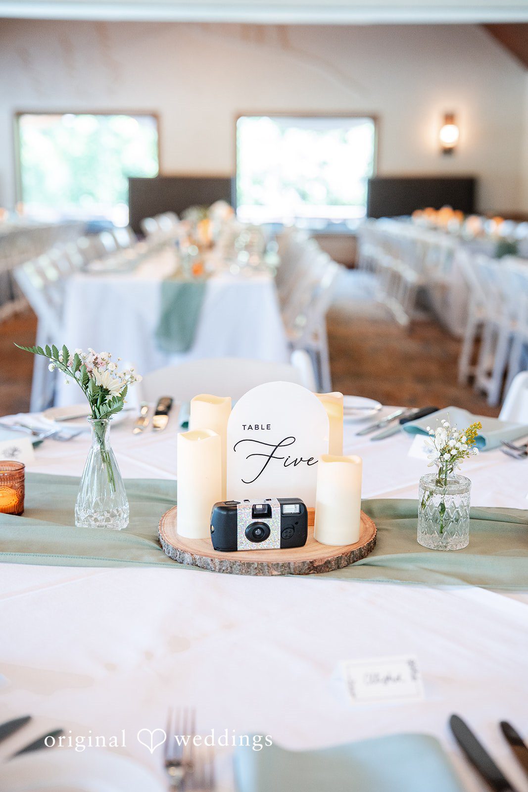 Mckenna + Ryan A close-up of a rustic reception table setting with candles and greenery.
