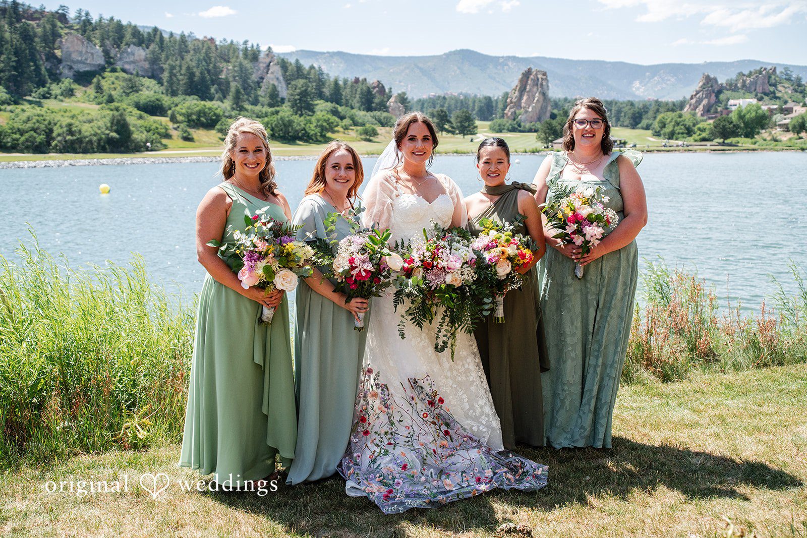 Mckenna + Ryan A group of bridesmaids in sage green dresses posing together on a grassy field.