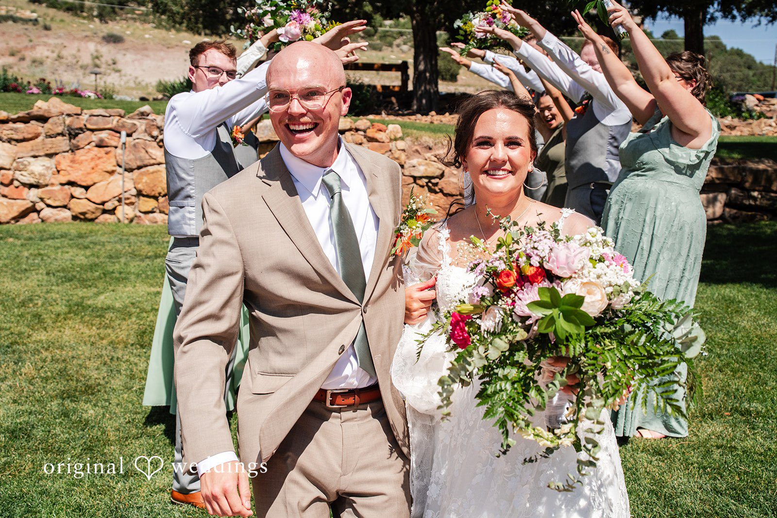 Mckenna + Ryan A bride and groom smiling while walking through an archway of raised hands.