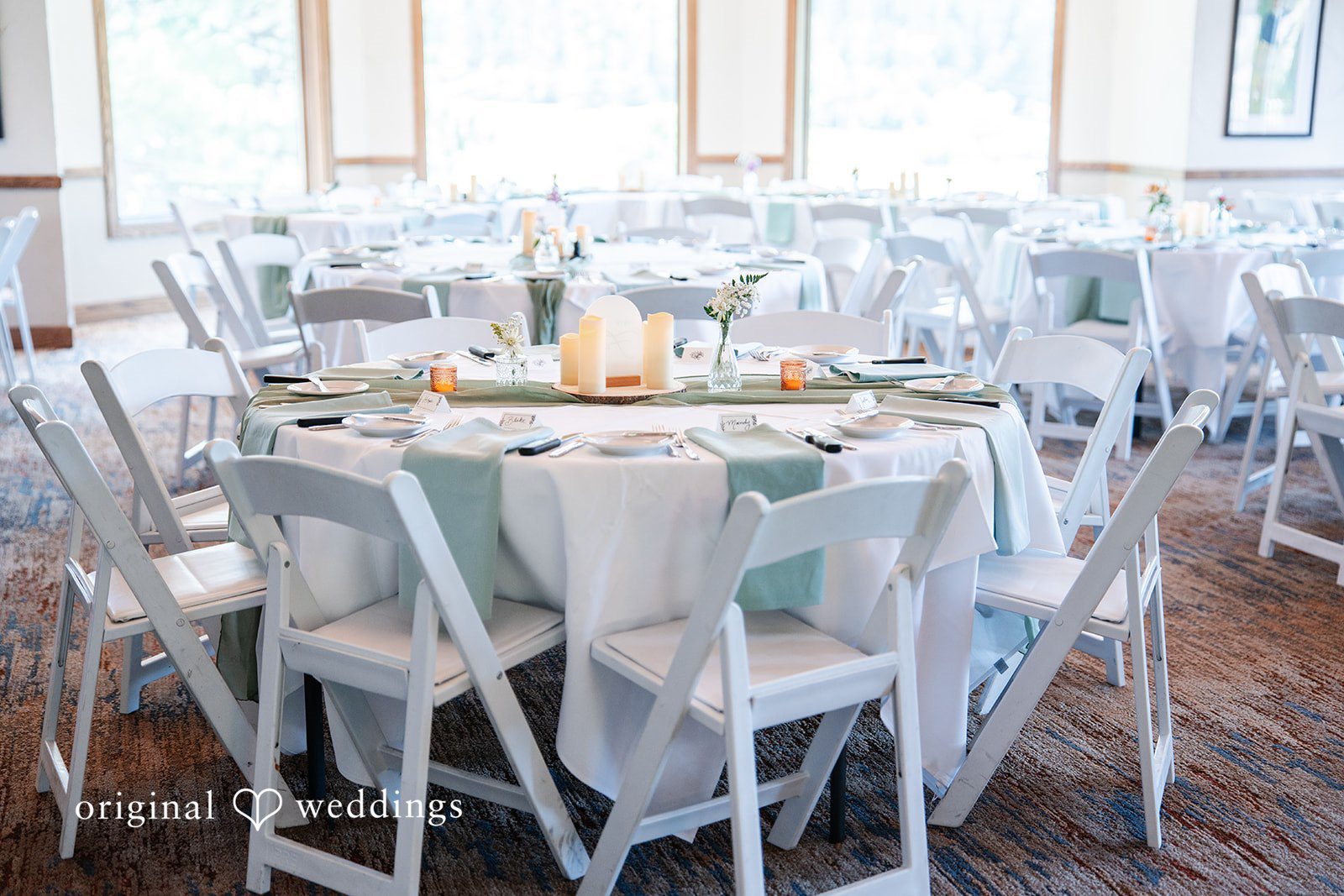 Mckenna + Ryan A round banquet table set with white linens and light blue napkins.