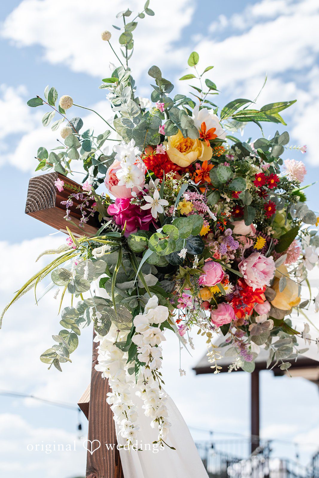 Mckenna + Ryan A vibrant floral arrangement featuring pink roses, eucalyptus, and orange flowers.
