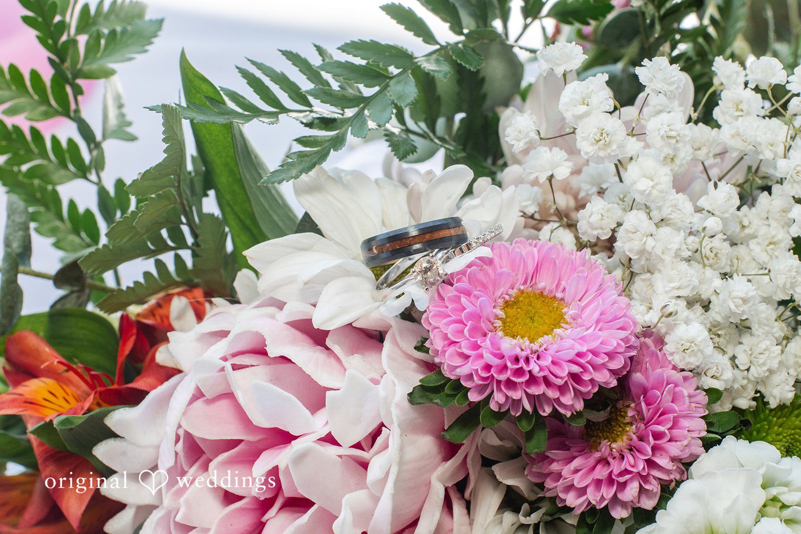 Mckenna + Ryan A close-up shot of a wedding ring nestled inside a bouquet of pink and white flowers.