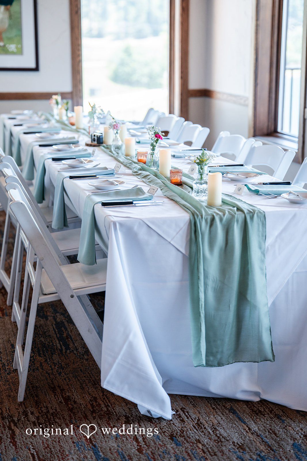 Mckenna + Ryan A long reception table covered in a white cloth with a light blue runner.