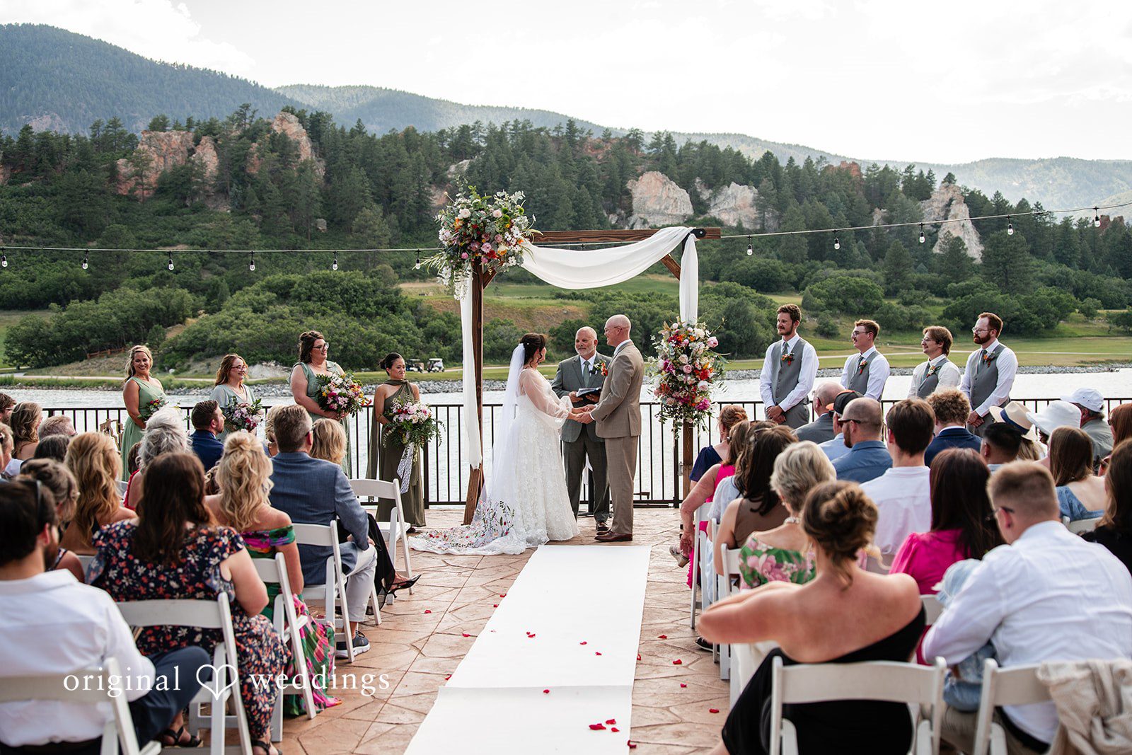 Mckenna + Ryan A wedding ceremony taking place on a white aisle under a wooden arch.