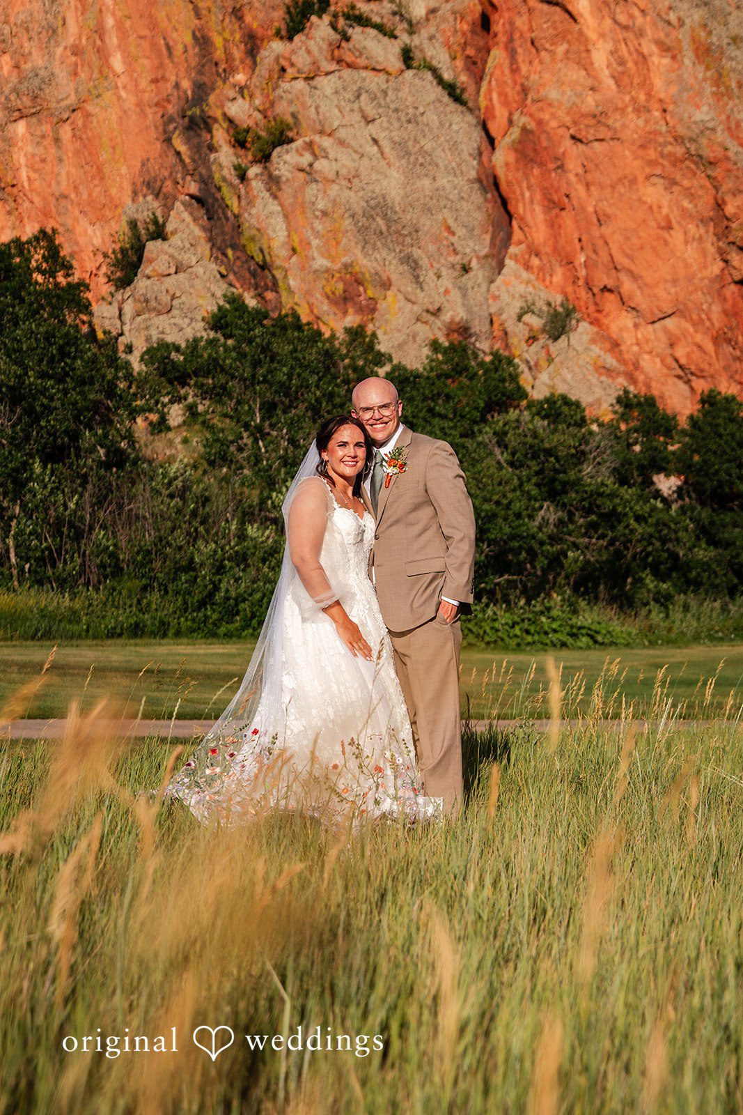 Mckenna + Ryan A bride and groom embracing in a sunlit field with tall grass.