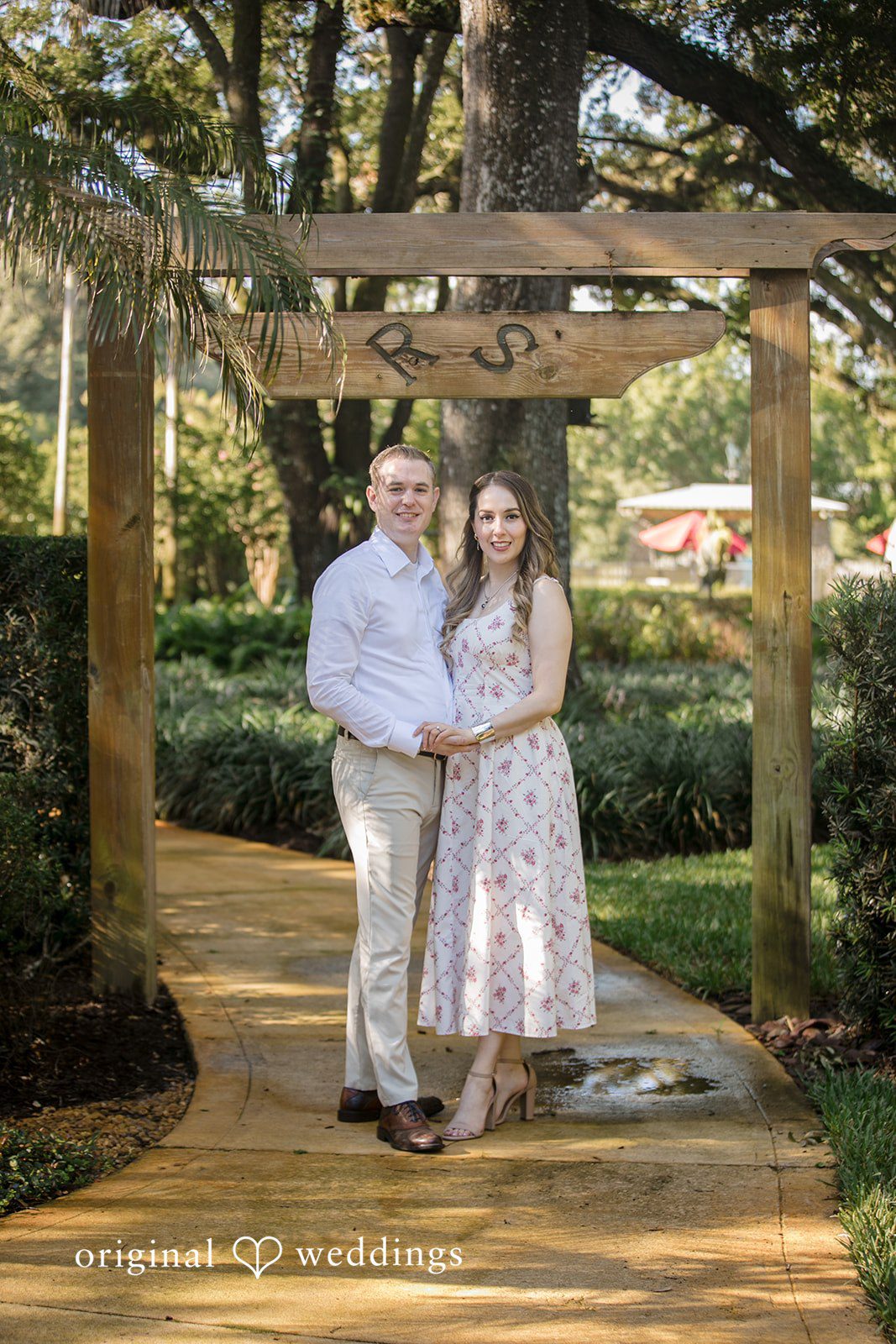 Couple standing on a wooden bridge surrounded by greenery.