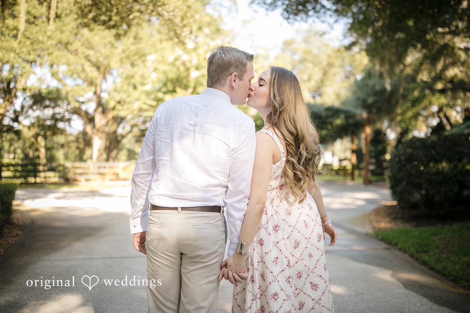 Couple share a kiss and walking away on a pathway.
