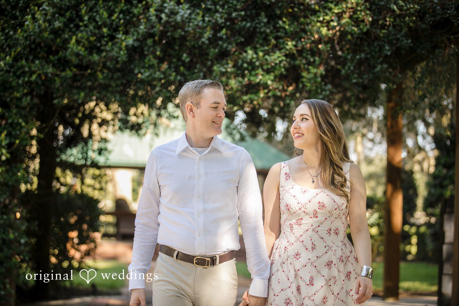 Couple holding hands and smile at each other while walking together.