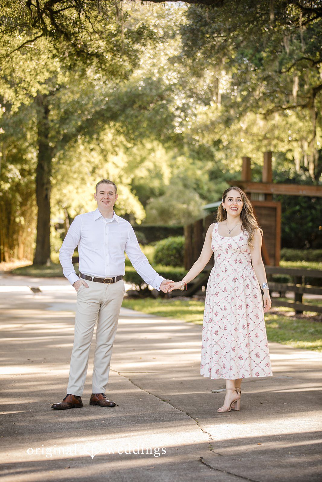 Couple holding hands while walking on a grassy lawn.
