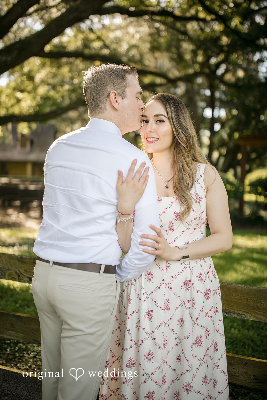 Man kissing a woman on the forehead while she smiles.