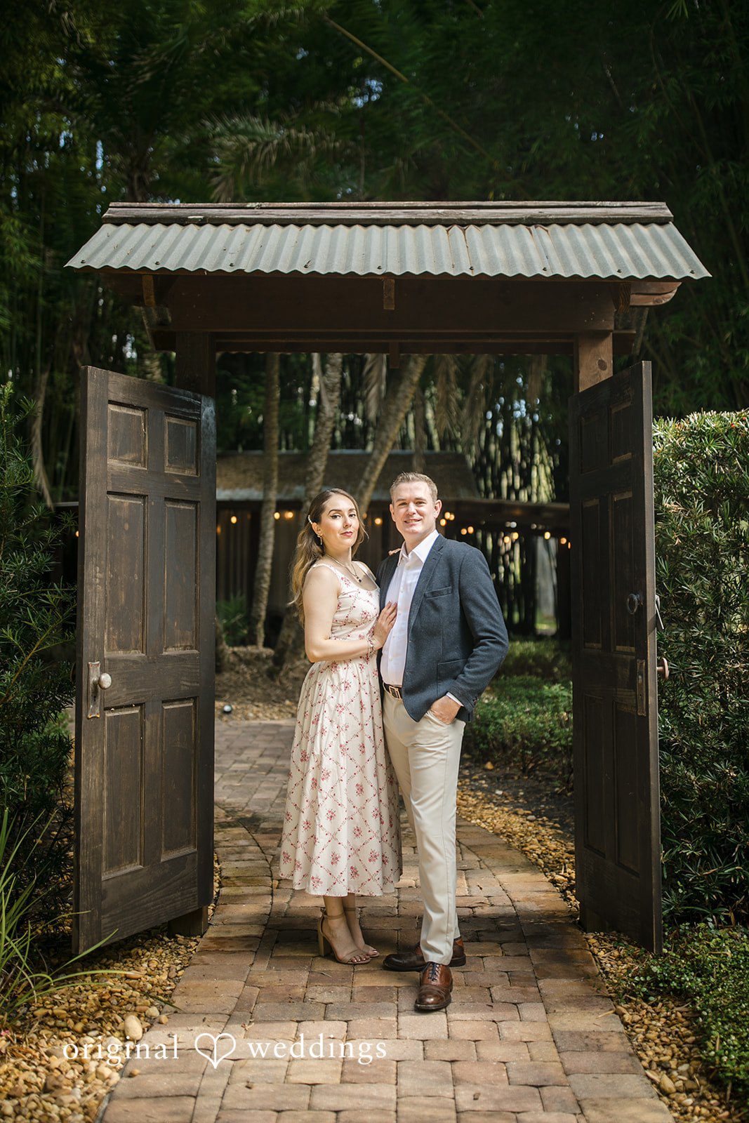 Couple posing together under a wooden archway entry.