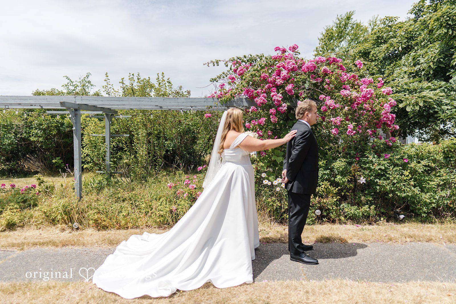 Madelyn + Connor A bride reaches out to tap a man in a black suit on the shoulder from behind during a first-look moment.