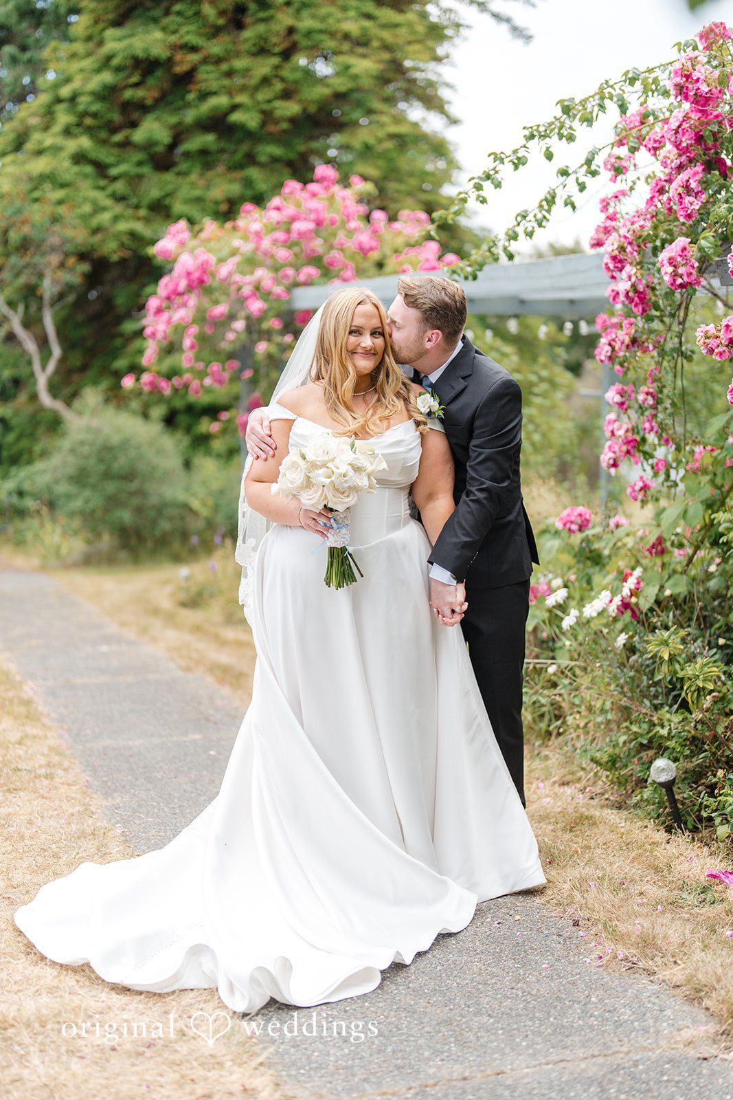 Madelyn + Connor A bride and groom sharing a laugh while standing together on a path.