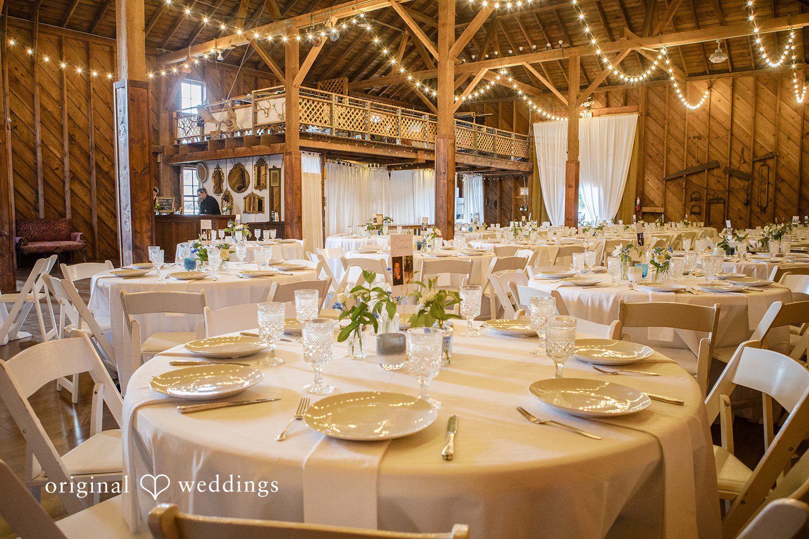 Madelyn + Connor A reception venue featuring round dining tables decorated with lit candles and floral centerpieces.