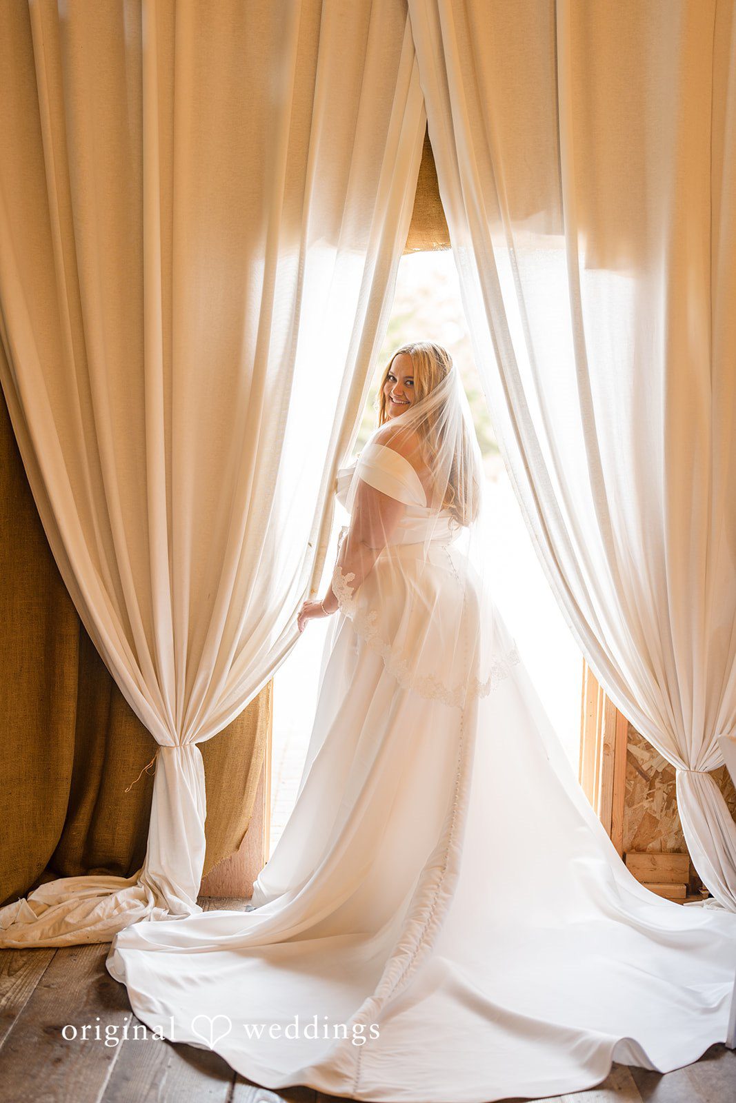 Madelyn + Connor A bride standing by a large doorway draped with sheer white curtains.