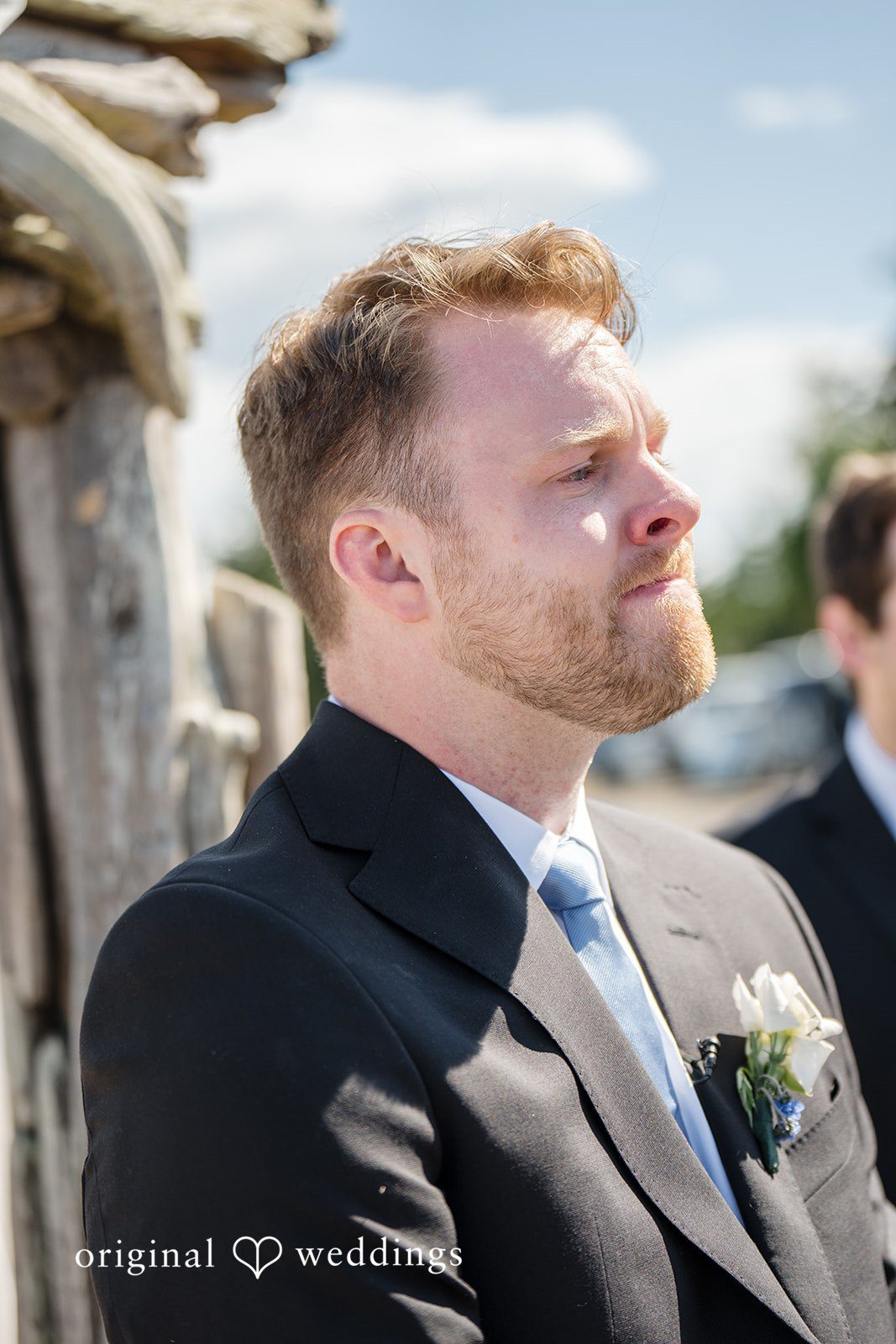 Madelyn + Connor A close-up portrait of a groom in a dark suit looking off into the distance.