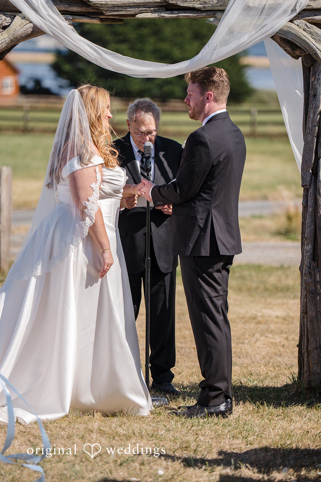 Madelyn + Connor A bride and groom standing before an officiant during their wedding ceremony.