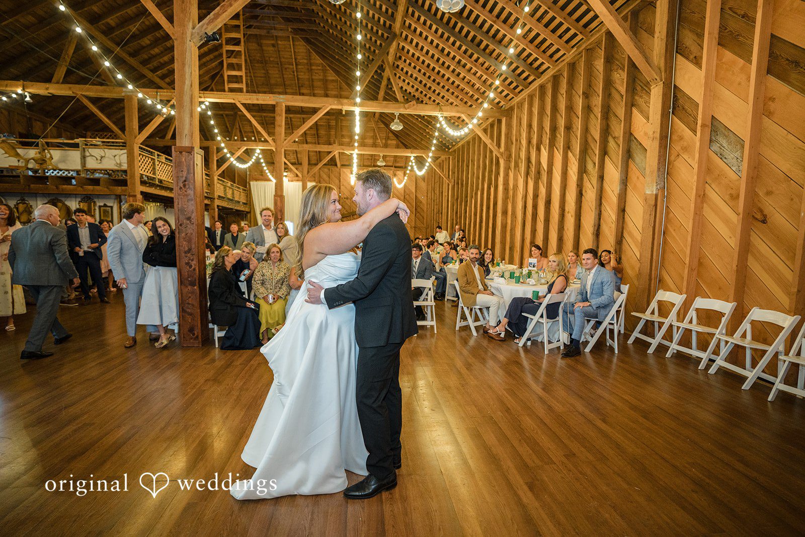Madelyn + Connor A bride and groom sharing their first dance in a large rustic barn venue.