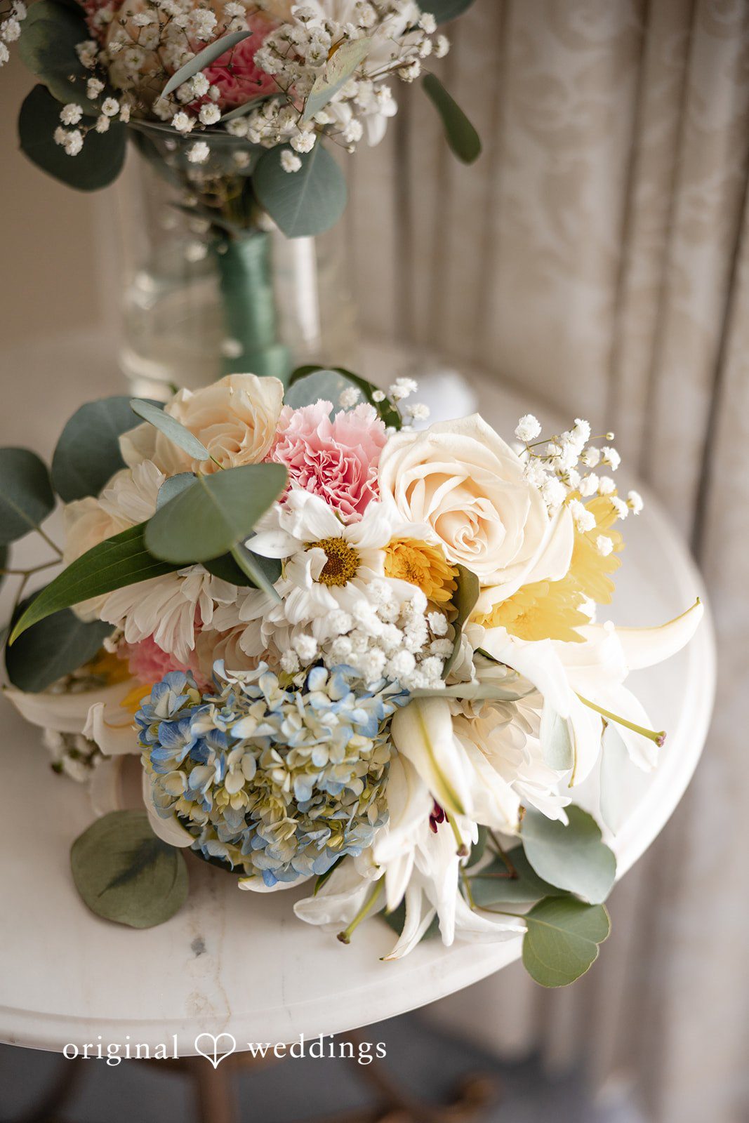 Maggie + Taylor A close-up view of a delicate floral centerpiece arrangement on a stand.