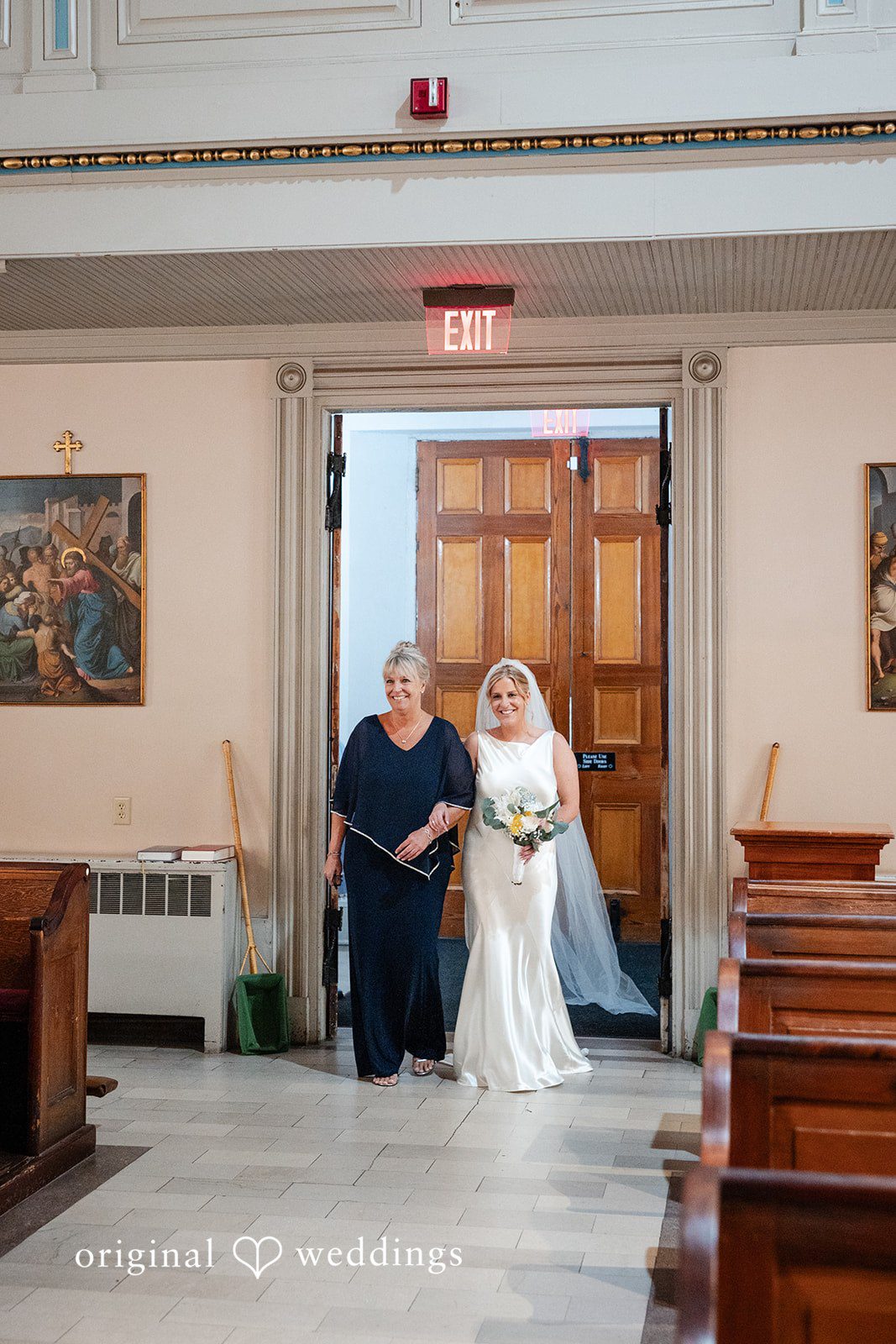 Maggie + Taylor A bride walked down a church aisle by women toward the altar.