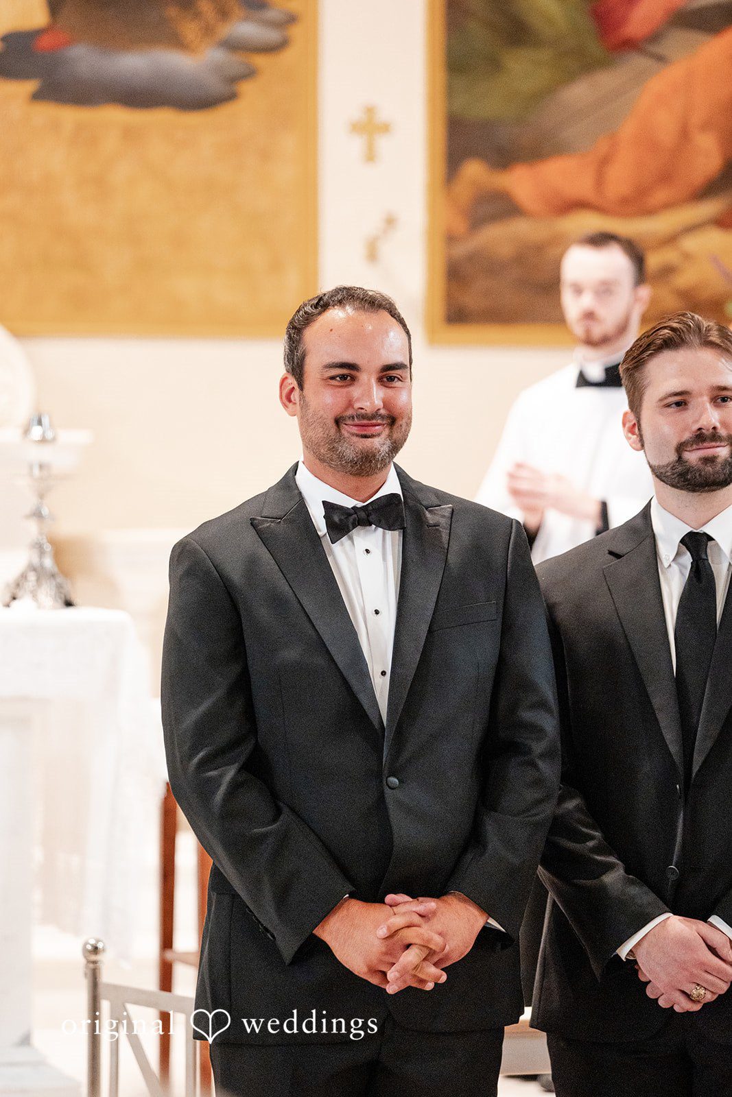 Maggie + Taylor A groom in a black tuxedo stands smiling alongside his groomsman.