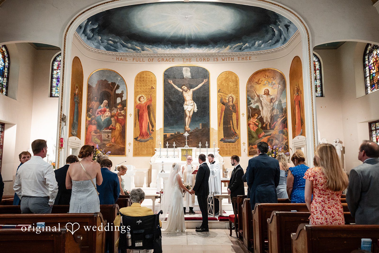 Maggie + Taylor A wedding ceremony takes place inside a historic church with beautiful painted murals.