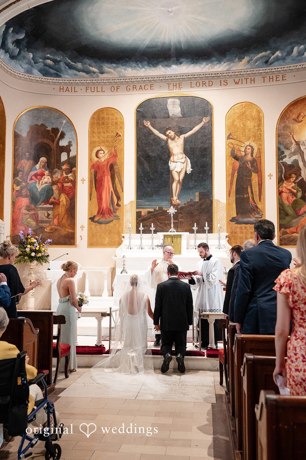 Maggie + Taylor Wedding guests watch the ceremony from their pews inside a church sanctuary.