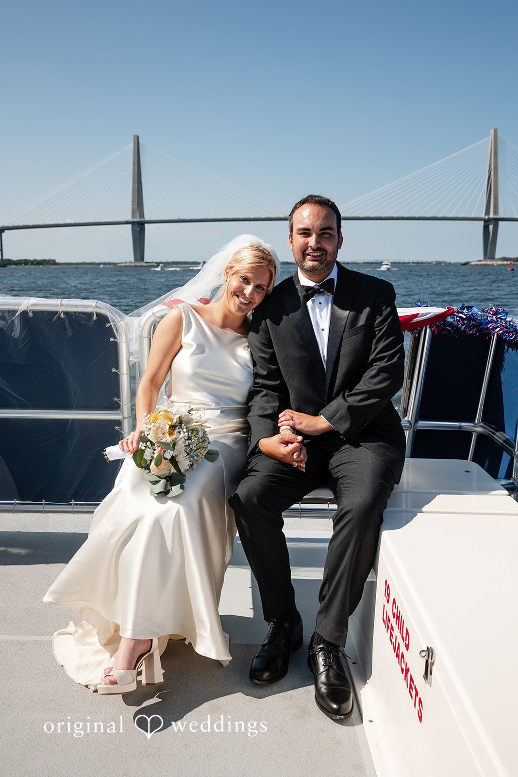 Maggie + Taylor A couple sits together on the deck of a boat with clear skies above.