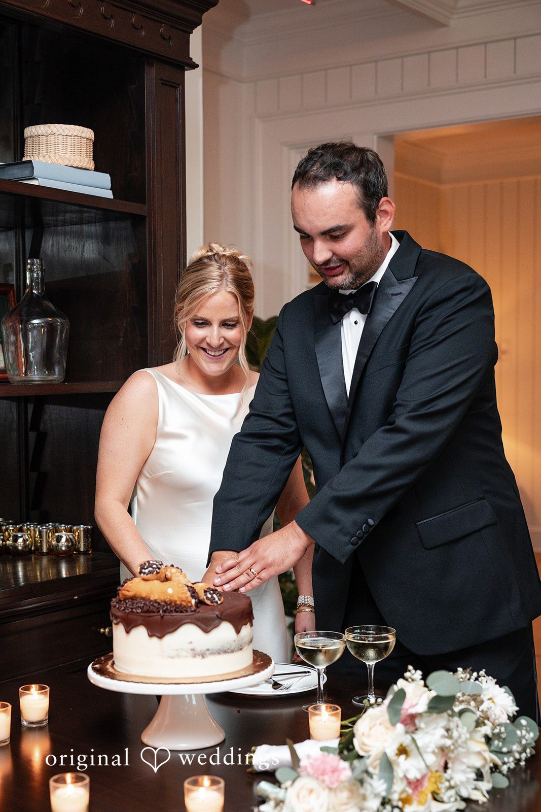 Maggie + Taylor A bride and groom cut their multi-tiered wedding cake together at the reception.