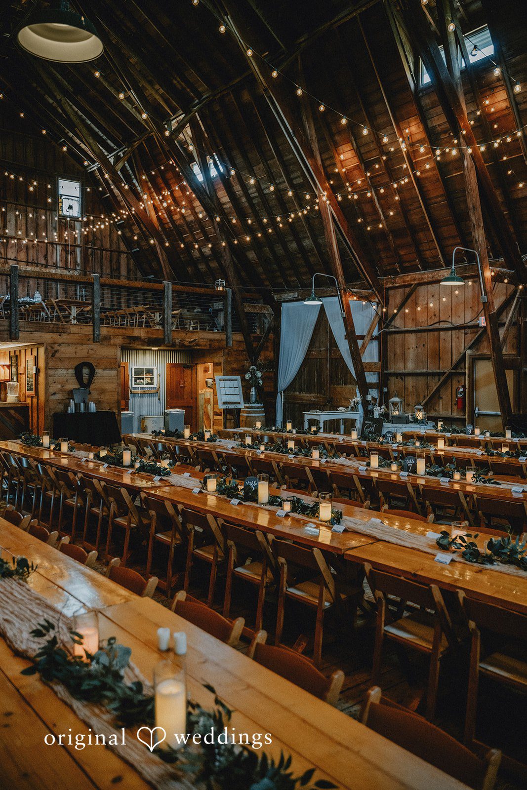 Samantha + Peyton Reception venue featuring long wooden tables under hanging lights.