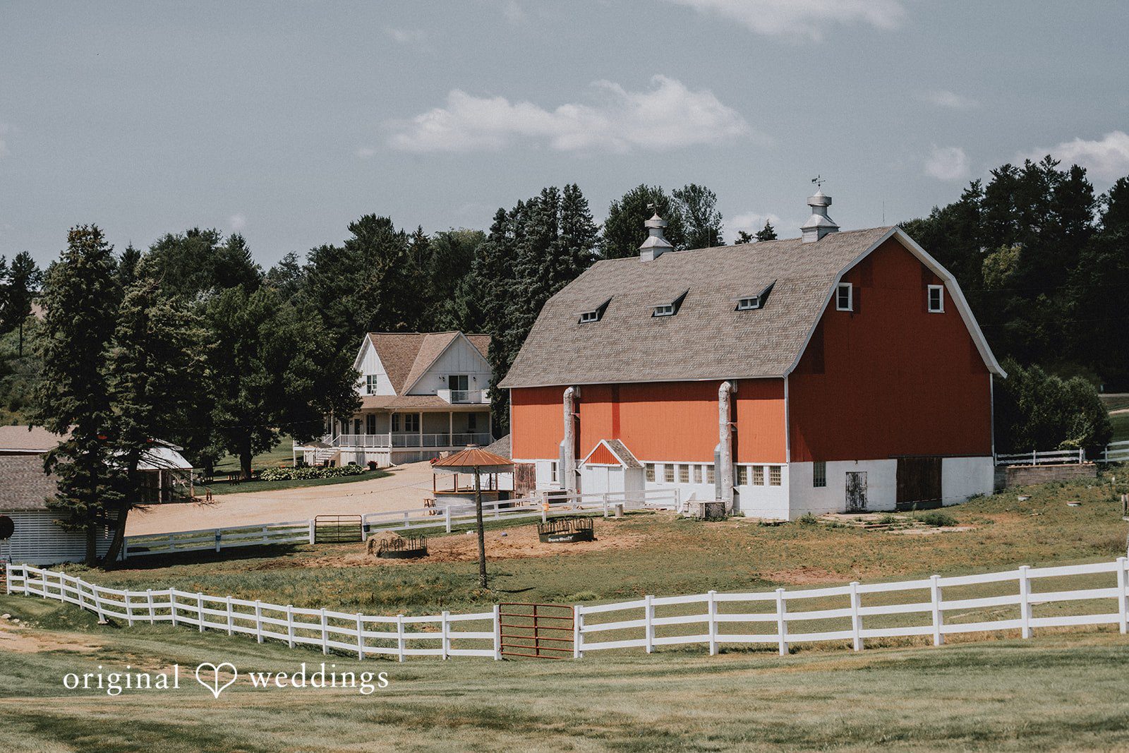 Samantha + Peyton Red barn on a grassy field with a white fence.