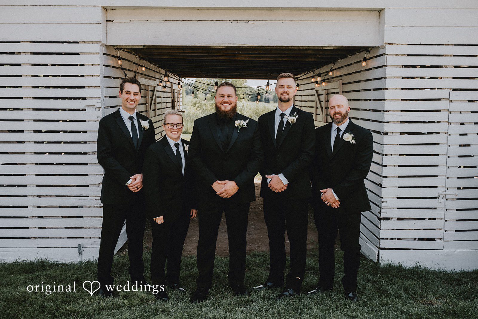 Samantha + Peyton Groomsmen standing in a row wearing classic black suits.